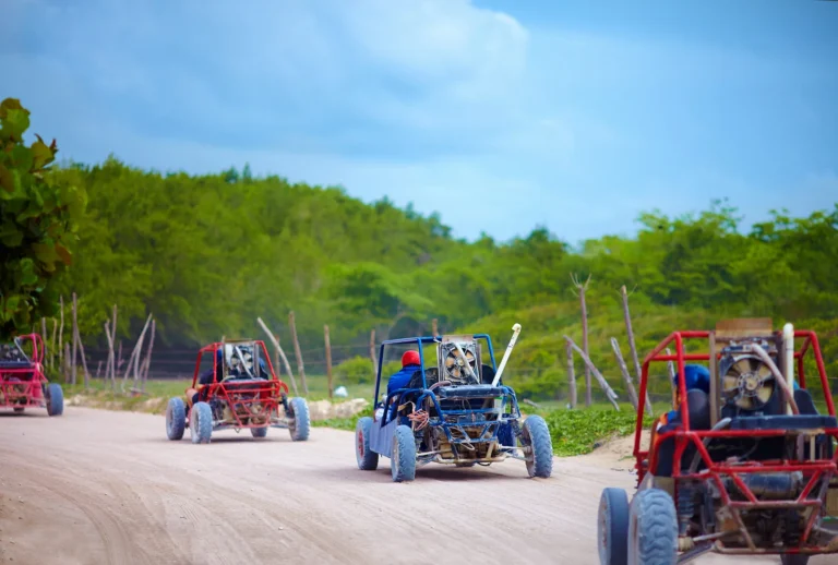 Gruppo di veicoli buggy su una polverosa strada di campagna durante un viaggio turistico estremo