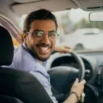 Cheerful middle-eastern taxi driver looking at back seat and smiling