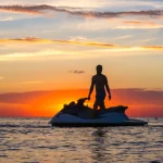 silhouette of a man on a jet ski in the sun