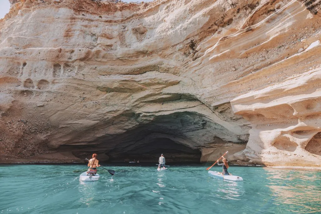 Eine Gruppe von Surfern betritt eine riesige Kalksteinhöhle an einer Meeresküste