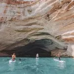 Group of sup boarders enters huge limestone cave on a sea coast
